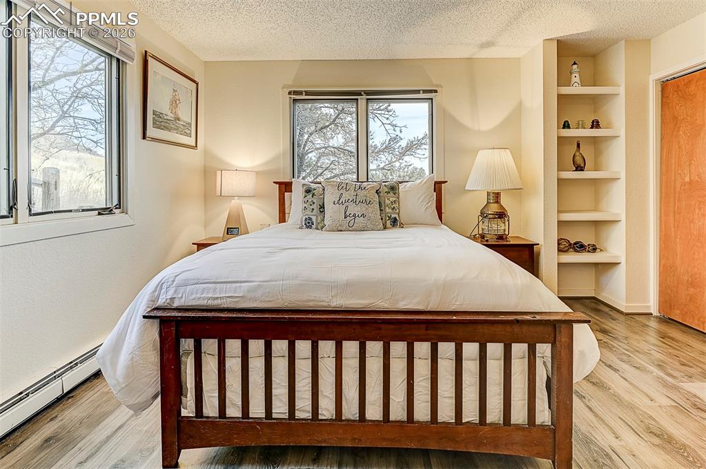 Image 31 of 41: Bedroom featuring baseboard heating, LVP floors, updated casement windows