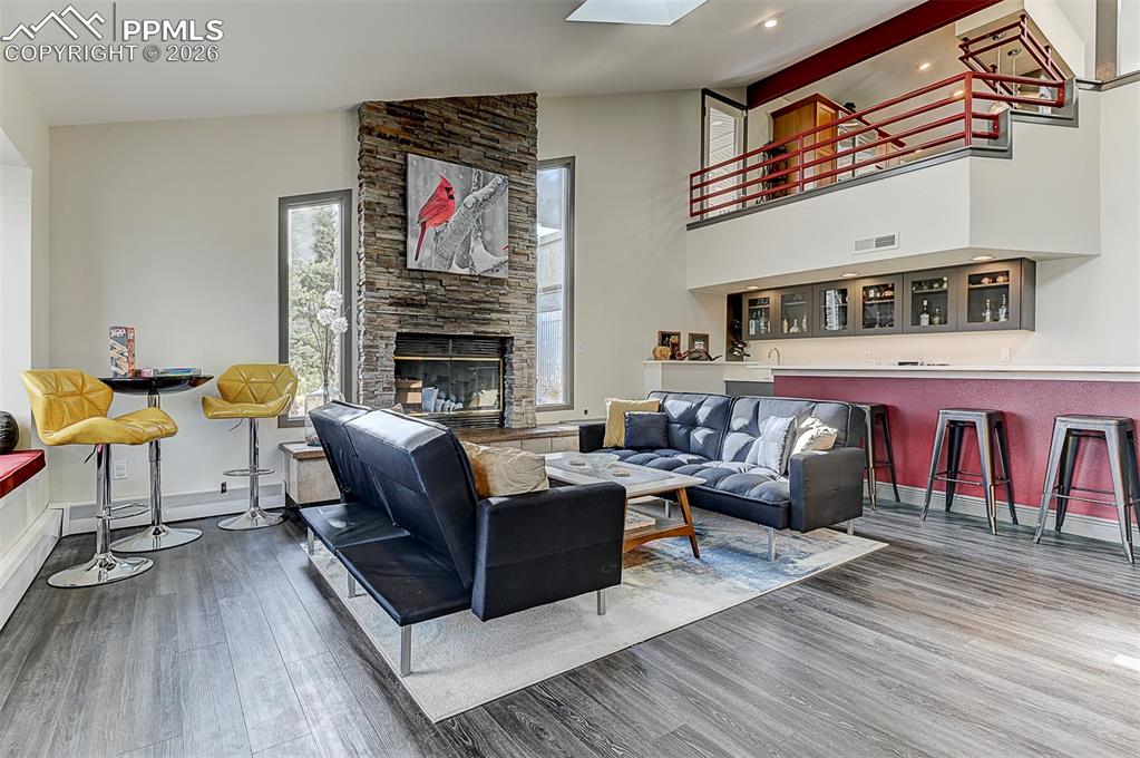 Image 5 of 41: Living area featuring wood finished floors, a fireplace, vaulted ceiling, a
