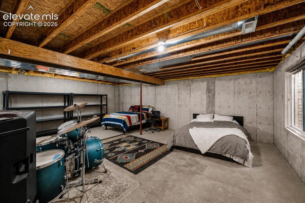 Image 14 of 20: Unfinished basement featuring exposed wood joists, concrete walls, and a vi