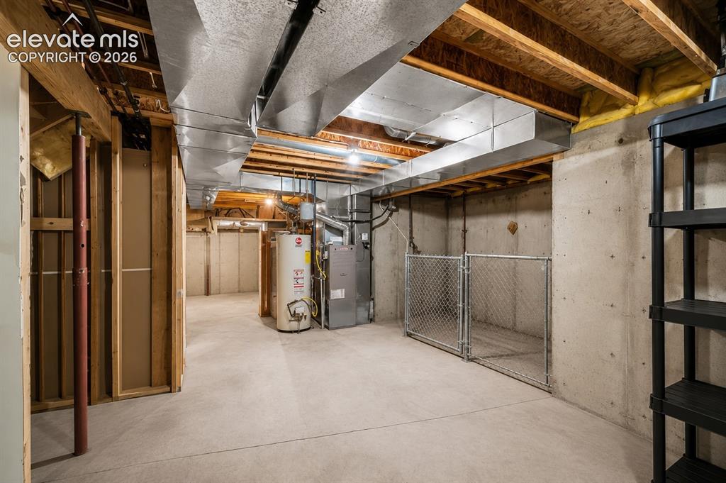 Image 15 of 20: Unfinished basement space featuring exposed wooden joists, concrete floorin