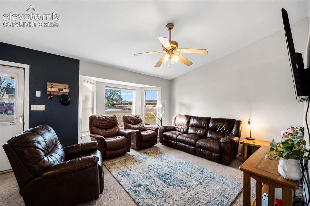 Image 2 of 20: Living area featuring a vaulted ceiling with a ceiling fan, a bay window, a