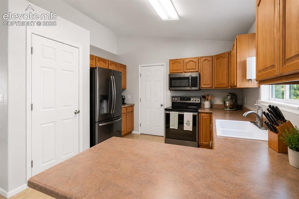 Image 6 of 20: Kitchen featuring wood cabinetry, a stainless steel sink, dark stainless st