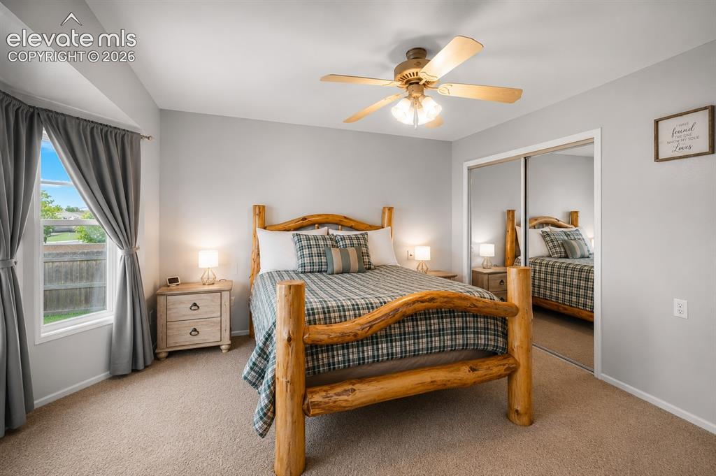 Image 8 of 20: Carpeted bedroom featuring a ceiling fan with light fixture, bay window wit