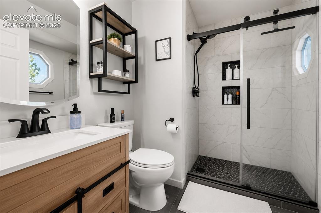 Image 9 of 20: Contemporary bathroom with a wood-finish vanity, white countertop, and matt