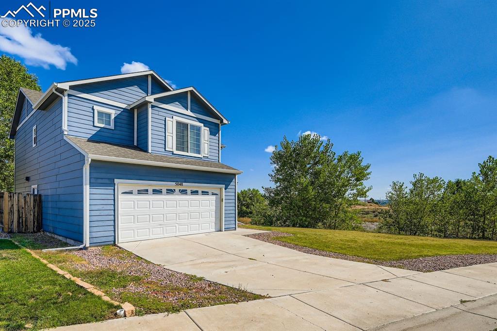 Caption: View of front of house featuring an attached garage, driveway, a front yard, and roof with shingles