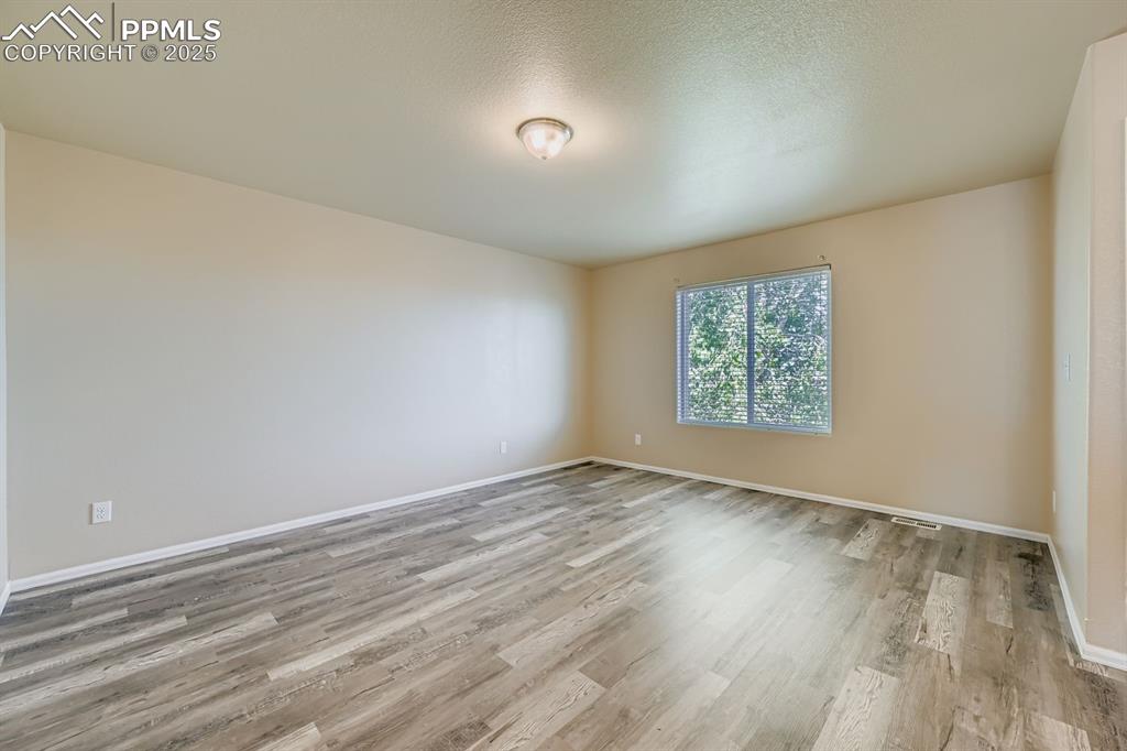 Image 21 of 26: Spare room with light wood-style flooring and a textured ceiling