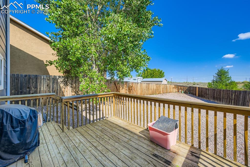 Image 26 of 26: Wooden deck featuring grilling area and a fenced backyard