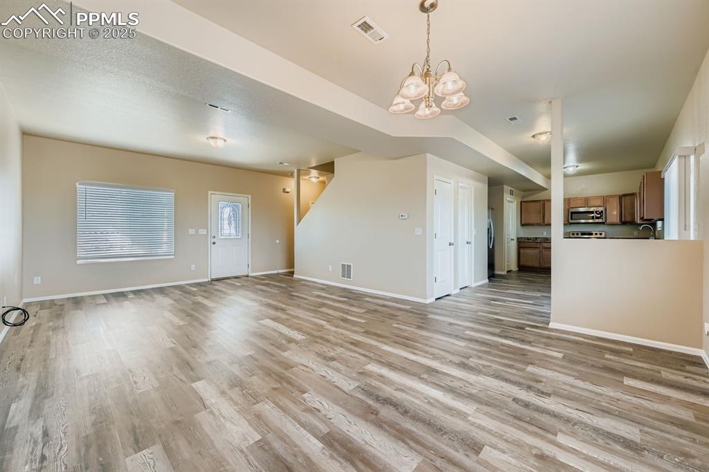 Image 6 of 26: Unfurnished living room featuring light wood-style flooring and a chandelie