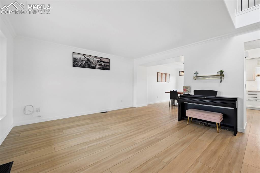 Image 11 of 50: Living area with ornamental molding and light wood-style flooring