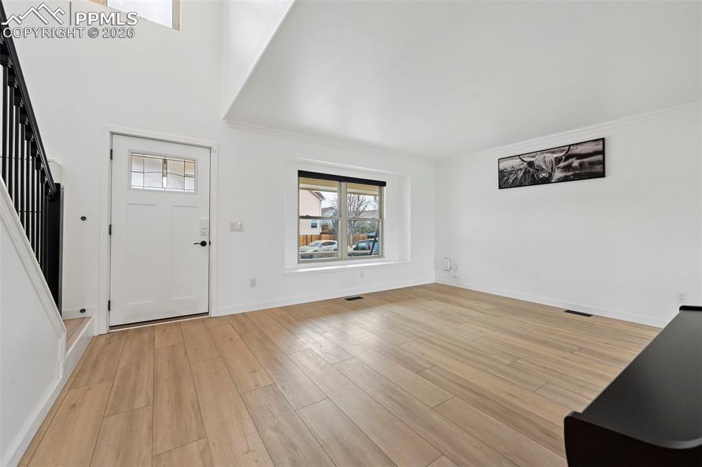 Image 13 of 50: Foyer entrance with light wood-style floors and a high ceiling