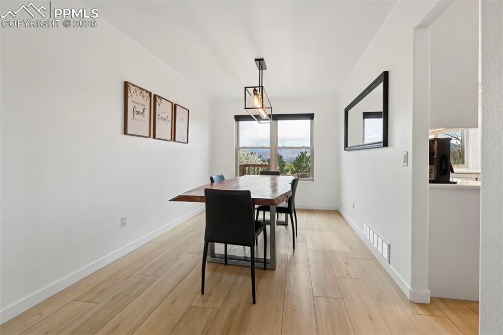 Image 15 of 50: Dining area with light wood-type flooring and crown molding