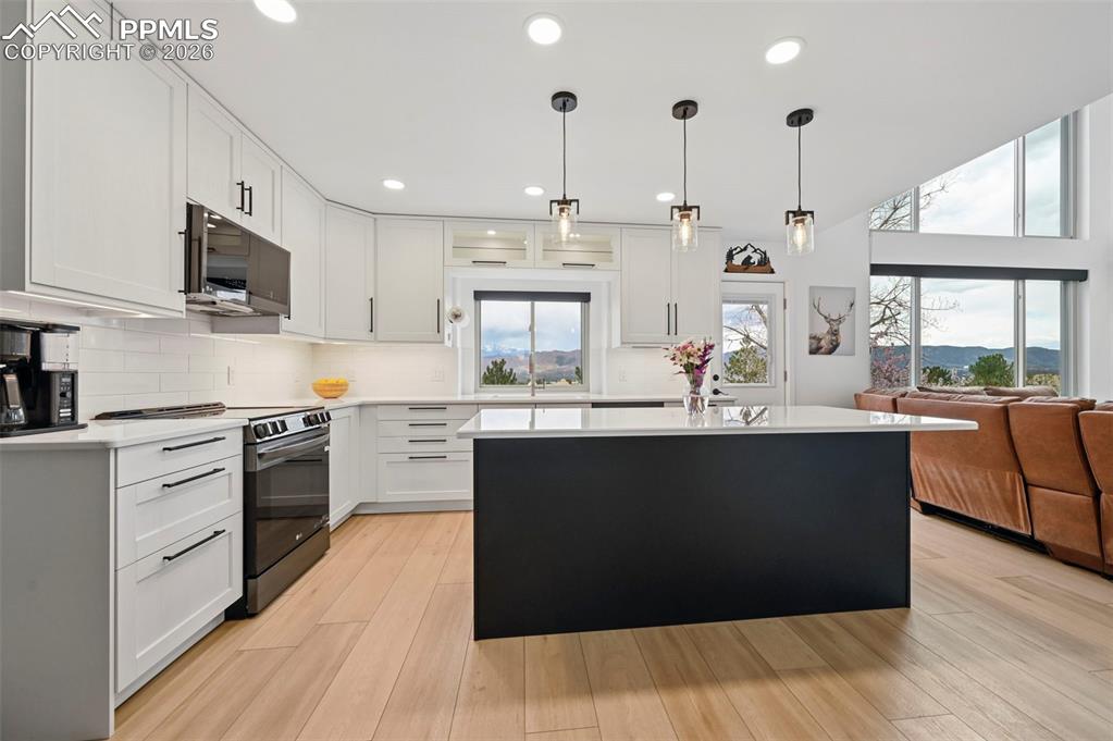 Image 18 of 50: Kitchen with electric range oven, a center island, stainless steel microwav