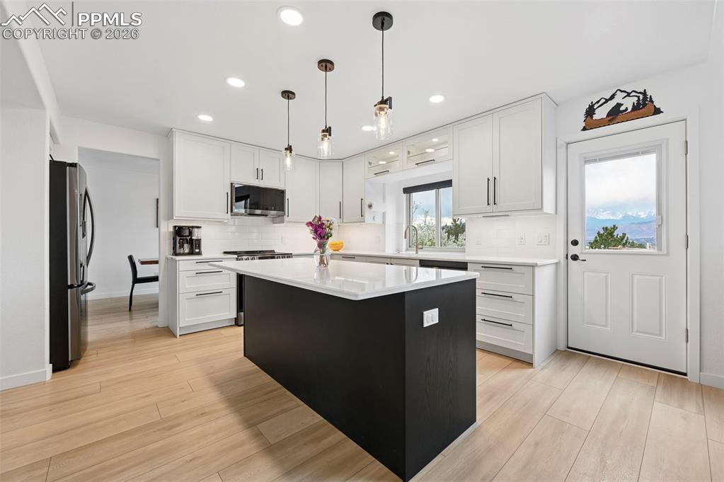 Image 19 of 50: Kitchen featuring a kitchen island, stainless steel appliances, light wood-