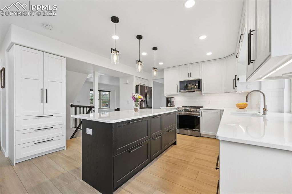 Image 21 of 50: Two tone kitchen with two tone cabinetry, stainless steel appliances, a cen