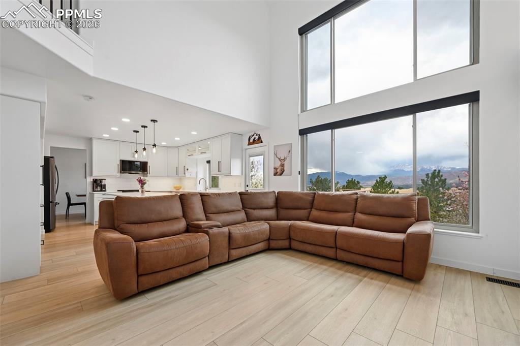 Image 25 of 50: Living room with a high ceiling, light wood-type flooring, and recessed lig