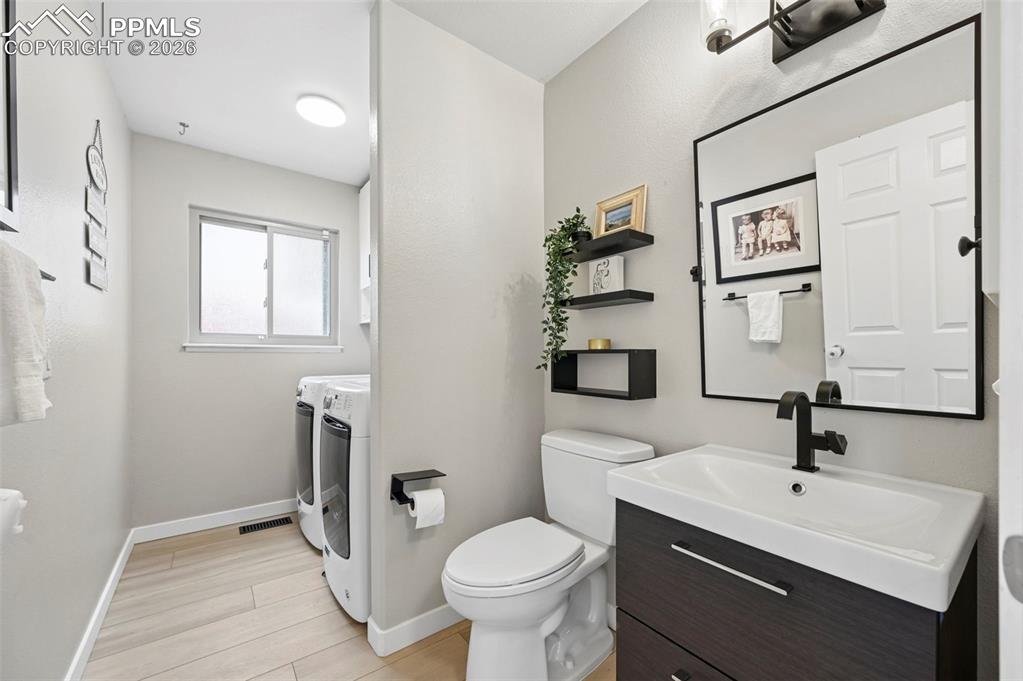 Image 27 of 50: Bathroom with washing machine and clothes dryer, vanity, and light wood-sty