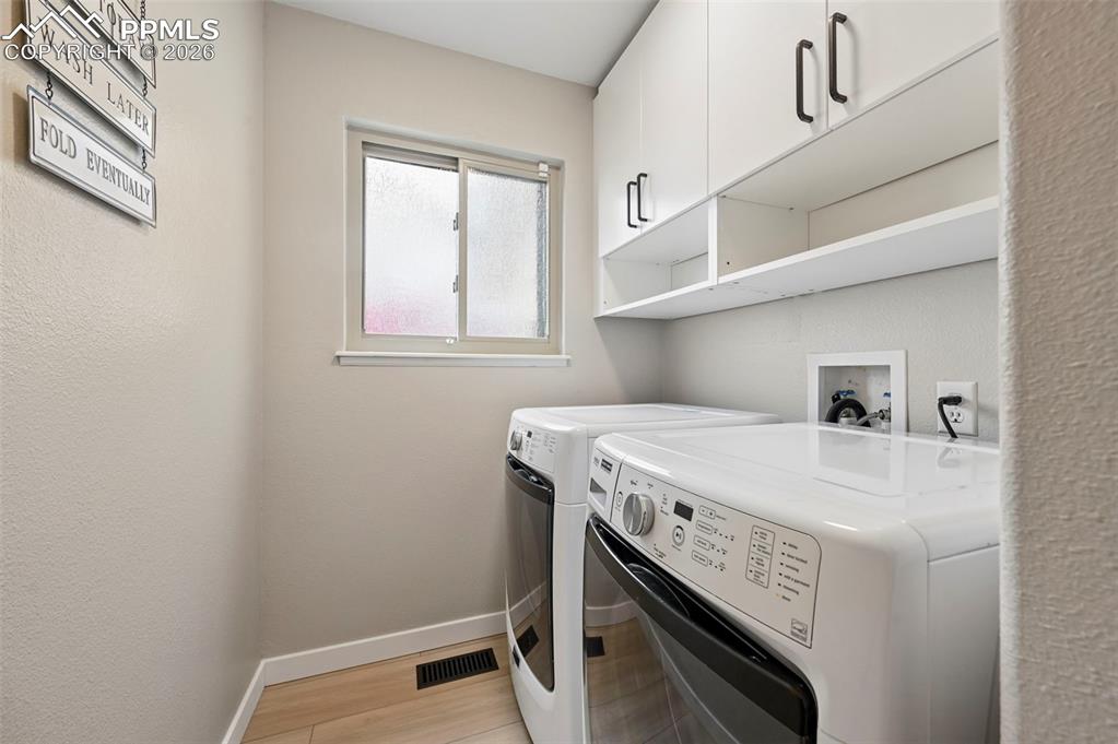 Image 28 of 50: Laundry room featuring a textured wall, cabinet space, washing machine and 