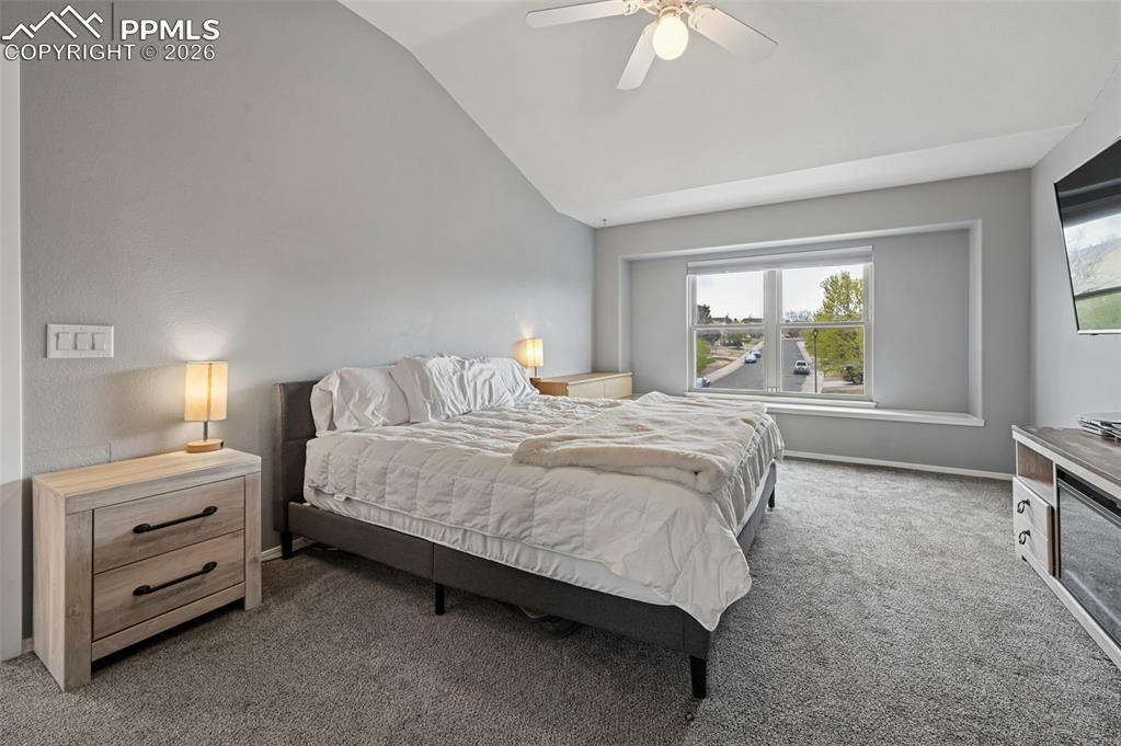 Image 30 of 50: Bedroom featuring dark colored carpet, ceiling fan, and lofted ceiling