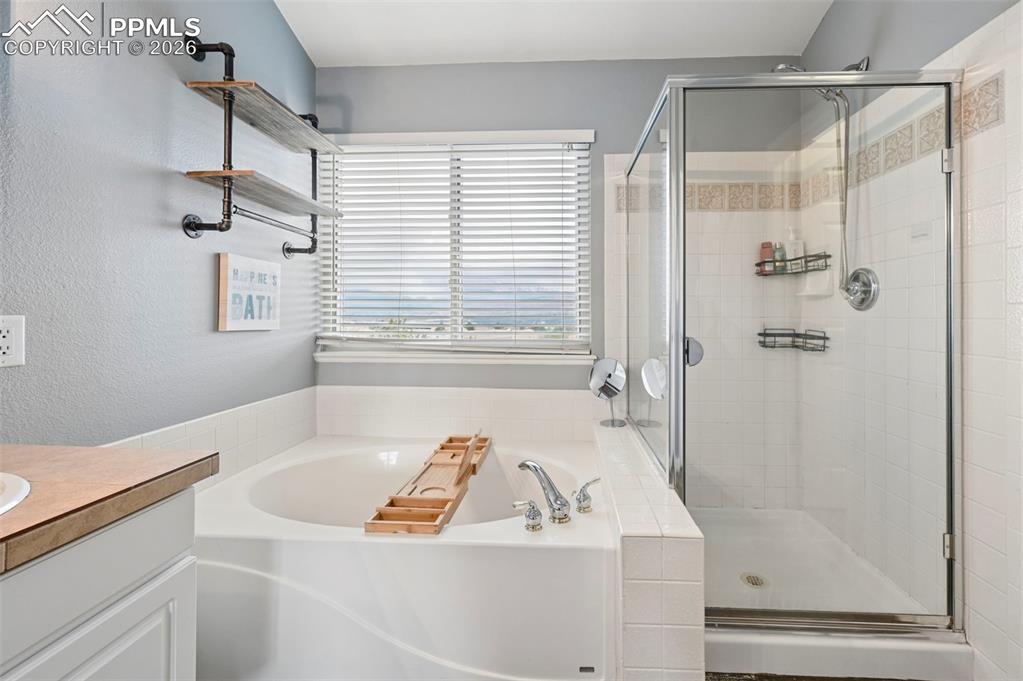Image 34 of 50: Full bath with a bath, vanity, a stall shower, and a textured wall