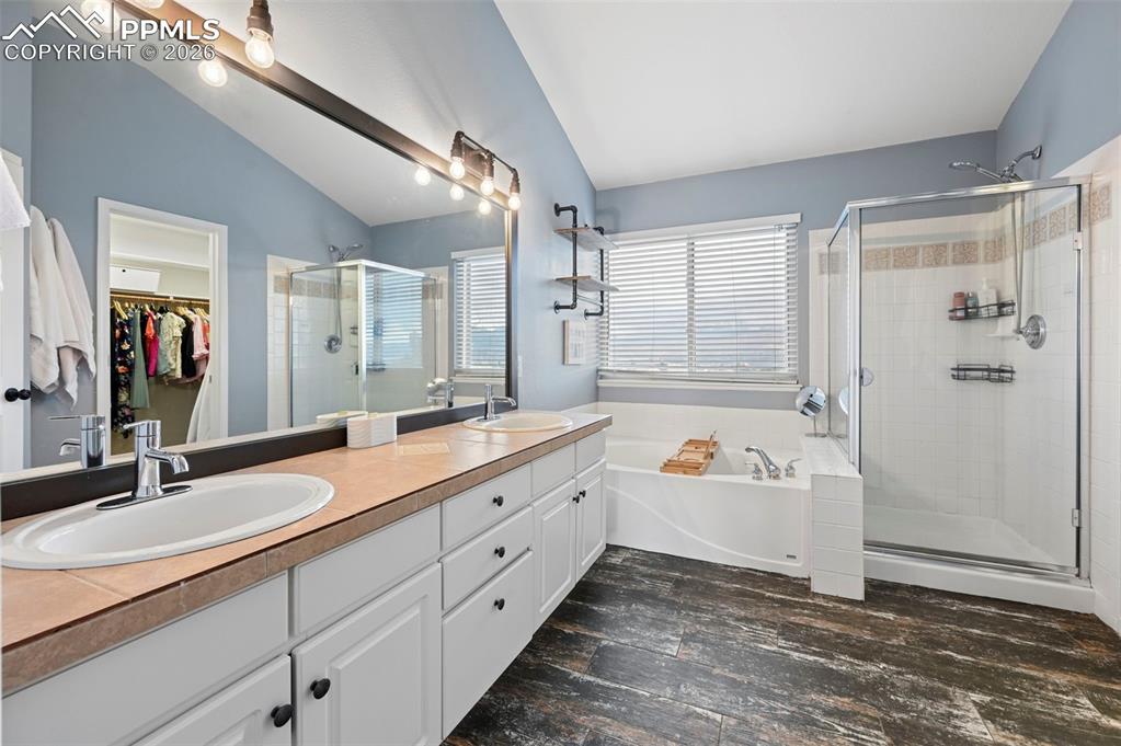 Image 35 of 50: Bathroom with a walk in closet, a garden tub, double vanity, a shower stall