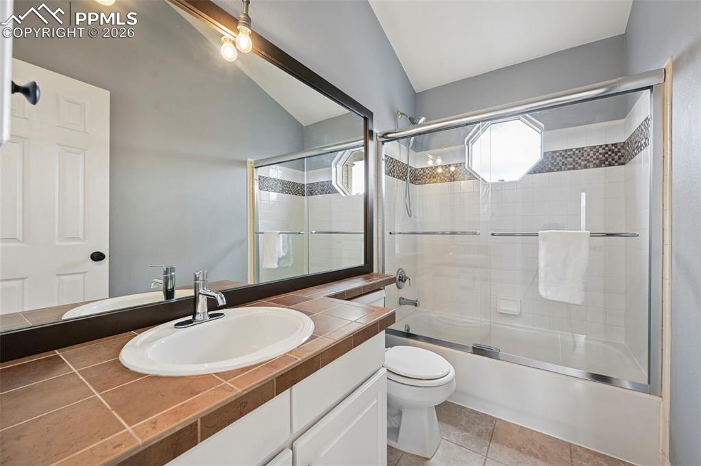 Image 36 of 50: Bathroom featuring vanity, bath / shower combo with glass door, lofted ceil