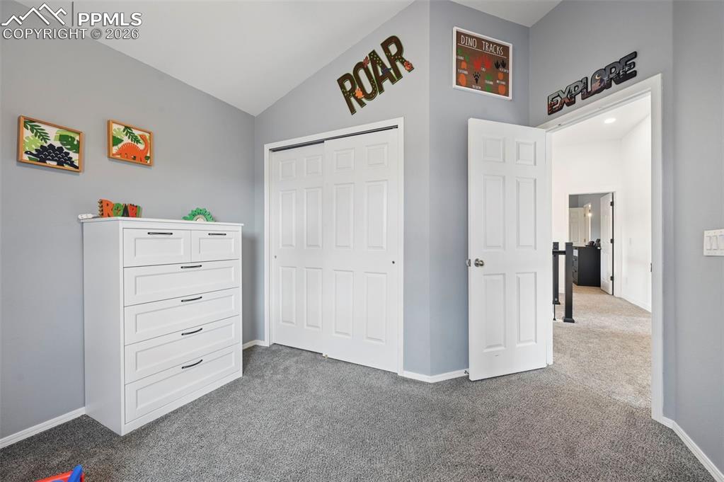 Image 40 of 50: Bedroom with dark carpet, lofted ceiling, and a closet