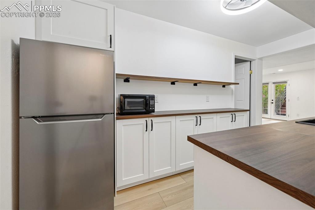 Image 41 of 50: Kitchen with freestanding refrigerator, wood counters, white cabinetry, bla