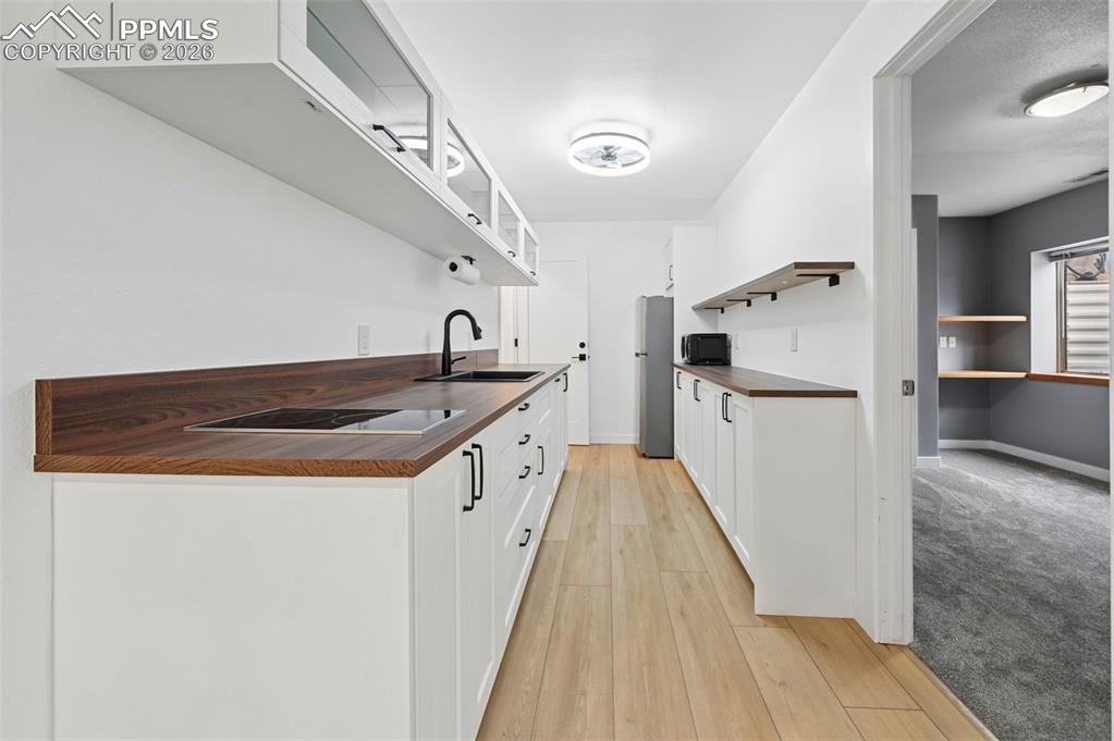 Image 43 of 50: Kitchen featuring white cabinets, light wood-style floors, black appliances