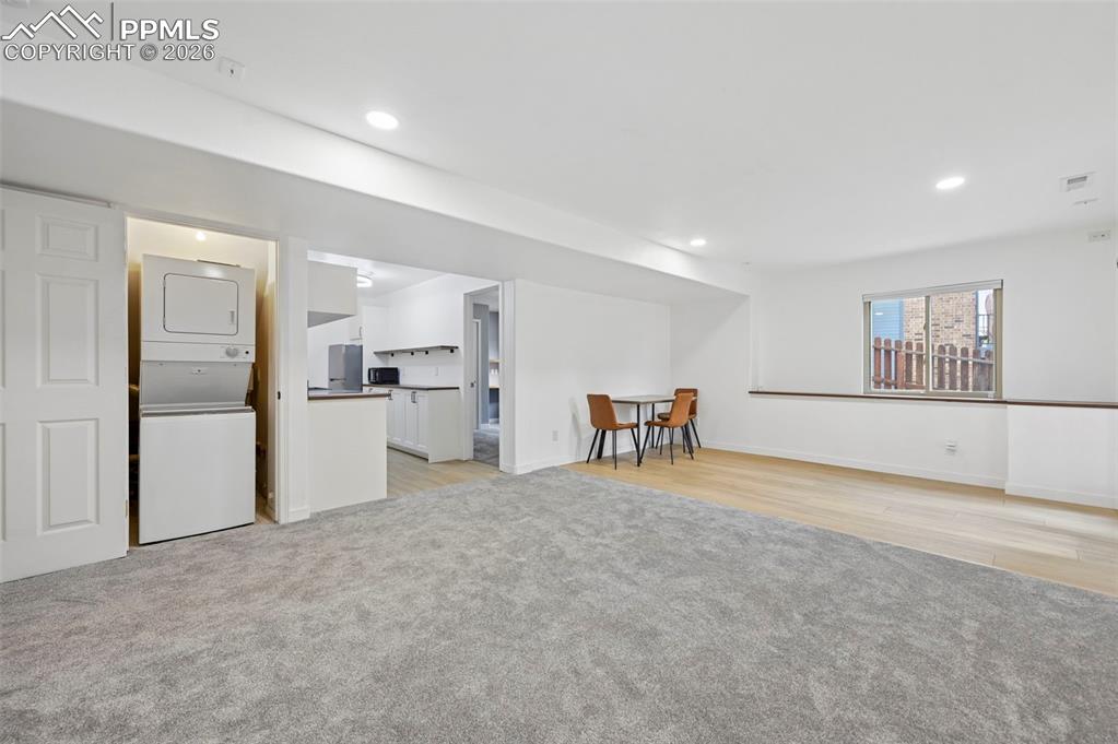 Image 47 of 50: Living room featuring light colored carpet, stacked washer and clothes drye