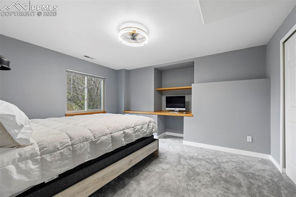 Image 48 of 50: Bedroom featuring light carpet and built in desk
