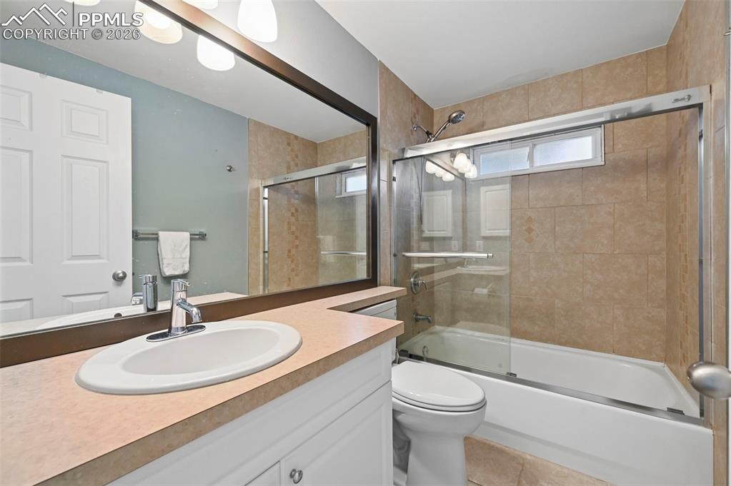 Image 50 of 50: Full bathroom with vanity, shower / bath combination with glass door, and l