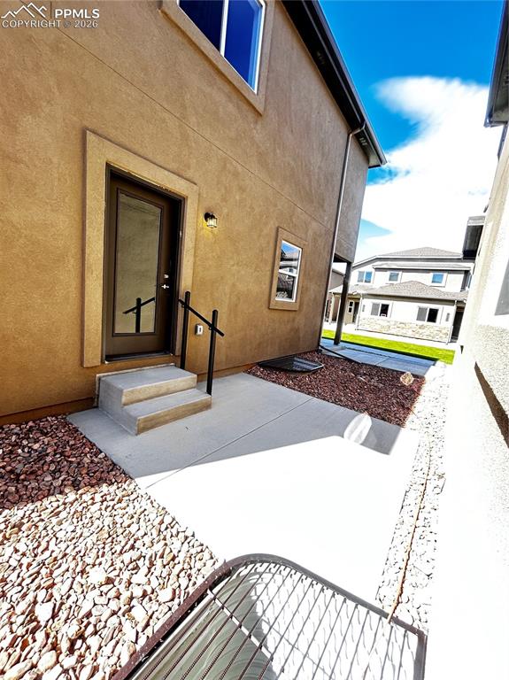 Image 11 of 14: Doorway to property featuring stucco siding and a patio
