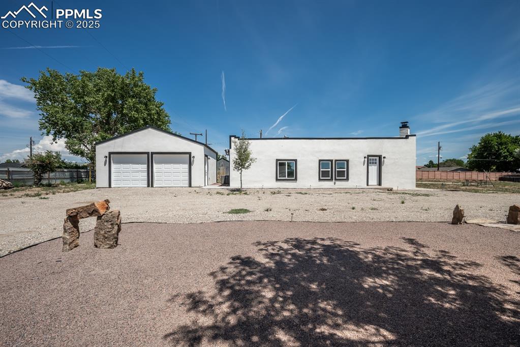 Caption: View of front of home with stucco siding, an outdoor structure, and a garage