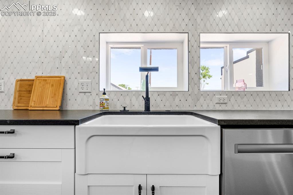 Image 17 of 50: Kitchen with dishwasher, dark granite  countertops, and white cabinets with