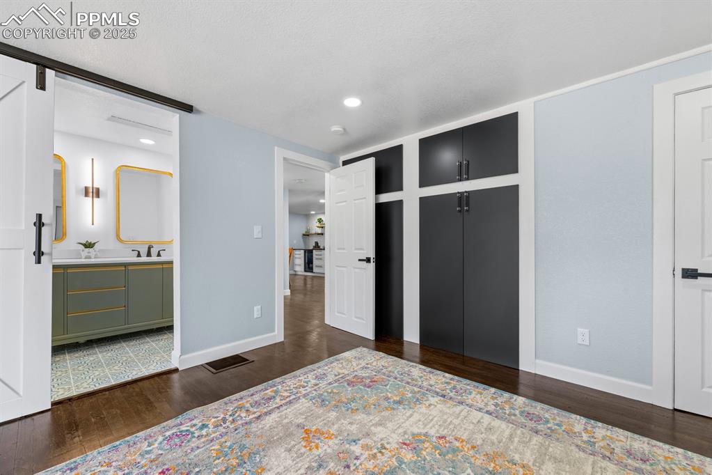Image 23 of 50: Bedroom featuring wood finished floors, a barn door, recessed lighting, and