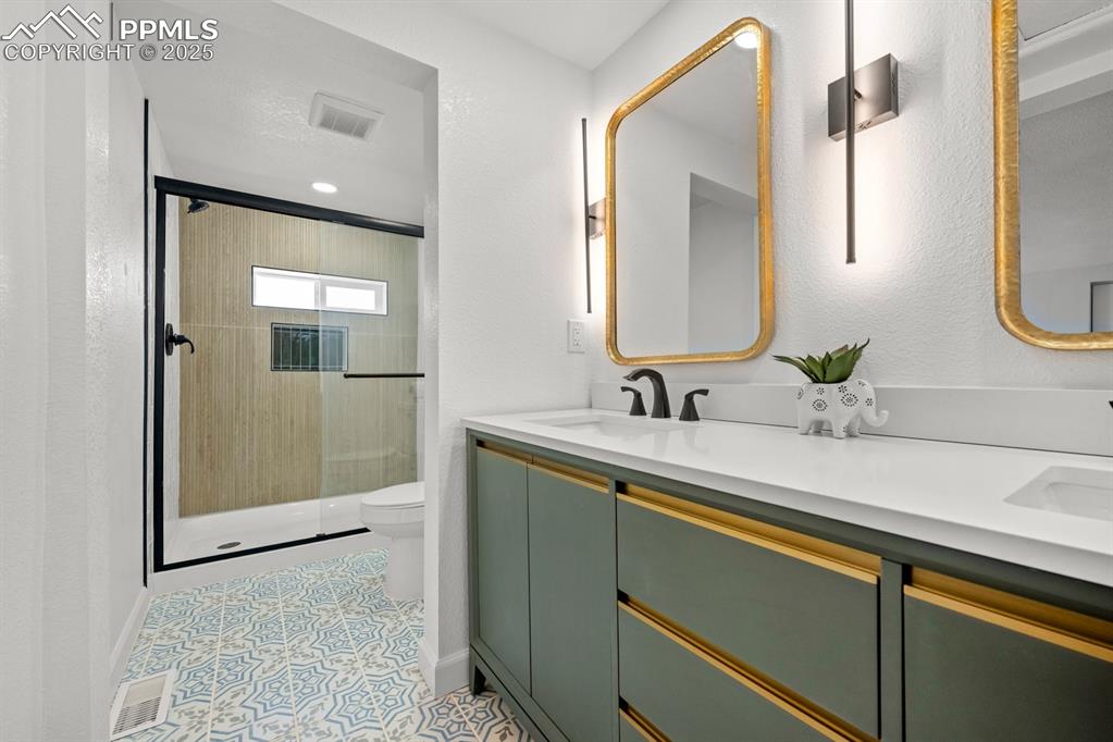 Image 24 of 50: Bathroom with a shower stall, double vanity, and a textured wall