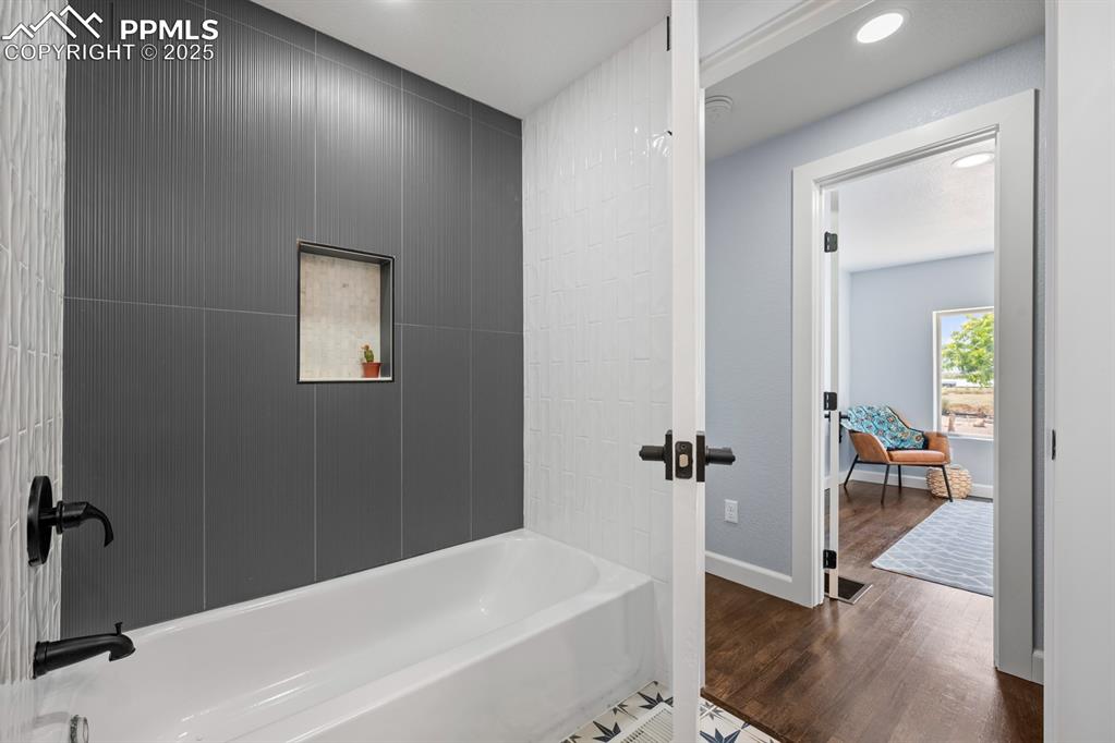 Image 32 of 50: Full bath featuring recessed lighting, wood finished floors, and bathing tu