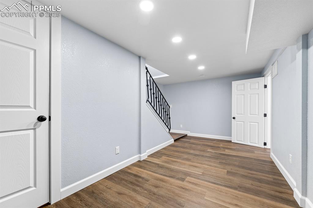 Image 36 of 50: Basement with wood finished floors, stairs, and recessed lighting