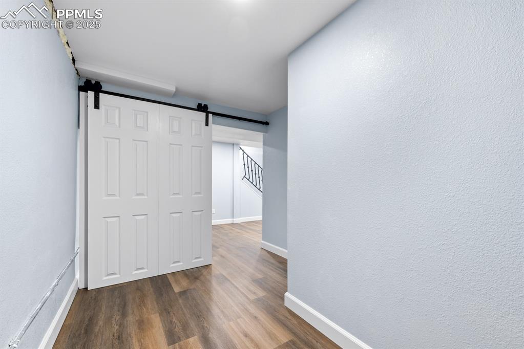 Image 40 of 50: Hall with dark wood-style flooring, a barn door, and a textured wall
