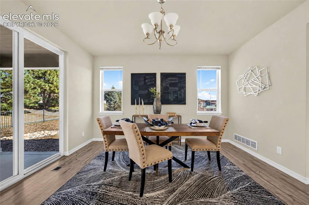 Image 10 of 41: Dining space with wood-laminate finish flooring, and multiple windows provi