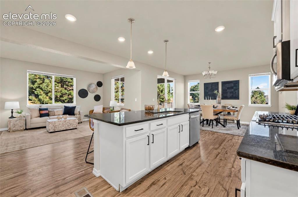 Image 15 of 41: Wood-finish flooring throughout, white cabinetry with dark hardware, dark c
