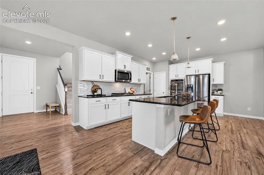 Image 17 of 41: Bright kitchen with recessed lighting, white cabinetry, a large kitchen isl