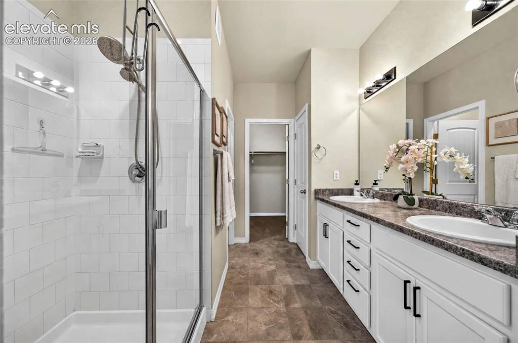 Image 23 of 41: Dual vanity with integrated sinks, white cabinetry with dark hardware, and