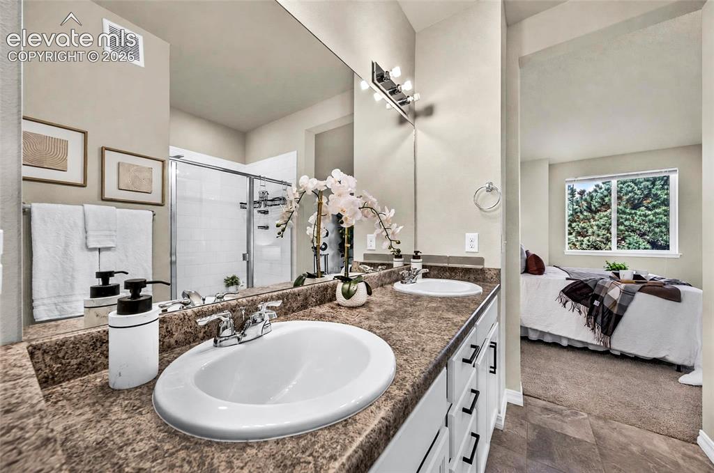 Image 24 of 41: Double vanity with integrated sinks, full-width mirror, and a shower with a