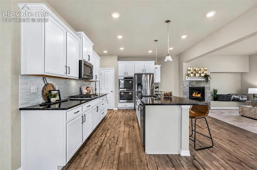 Image 6 of 41: Gourmet kitchen featuring white cabinetry, granite countertops, a large isl
