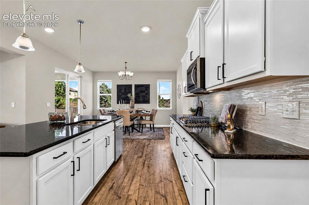 Image 7 of 41: Kitchen featuring white cabinetry, dark countertops, wood-finish flooring,