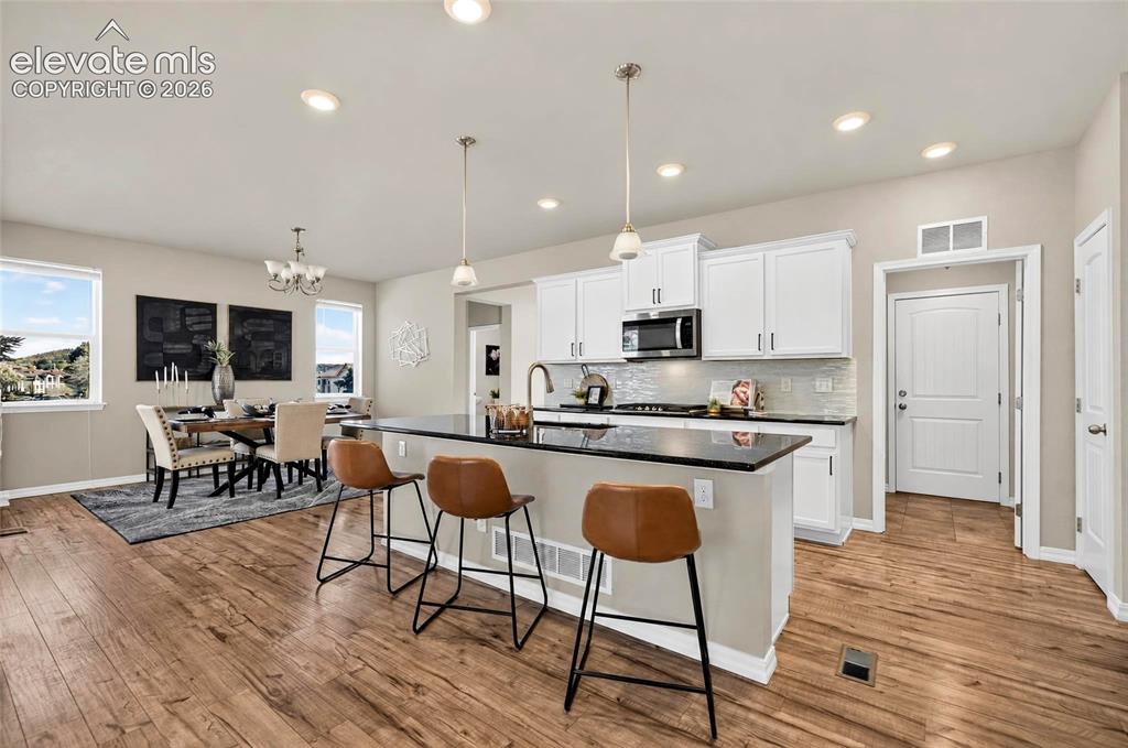 Image 9 of 41: Wood-finish flooring throughout, white cabinetry, dark countertop island, s