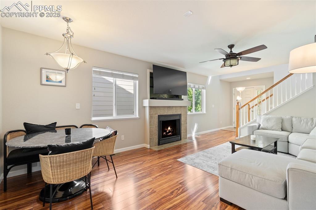 Image 4 of 38: Living room with a gas fireplace, ceiling fan and adjoining dining space
