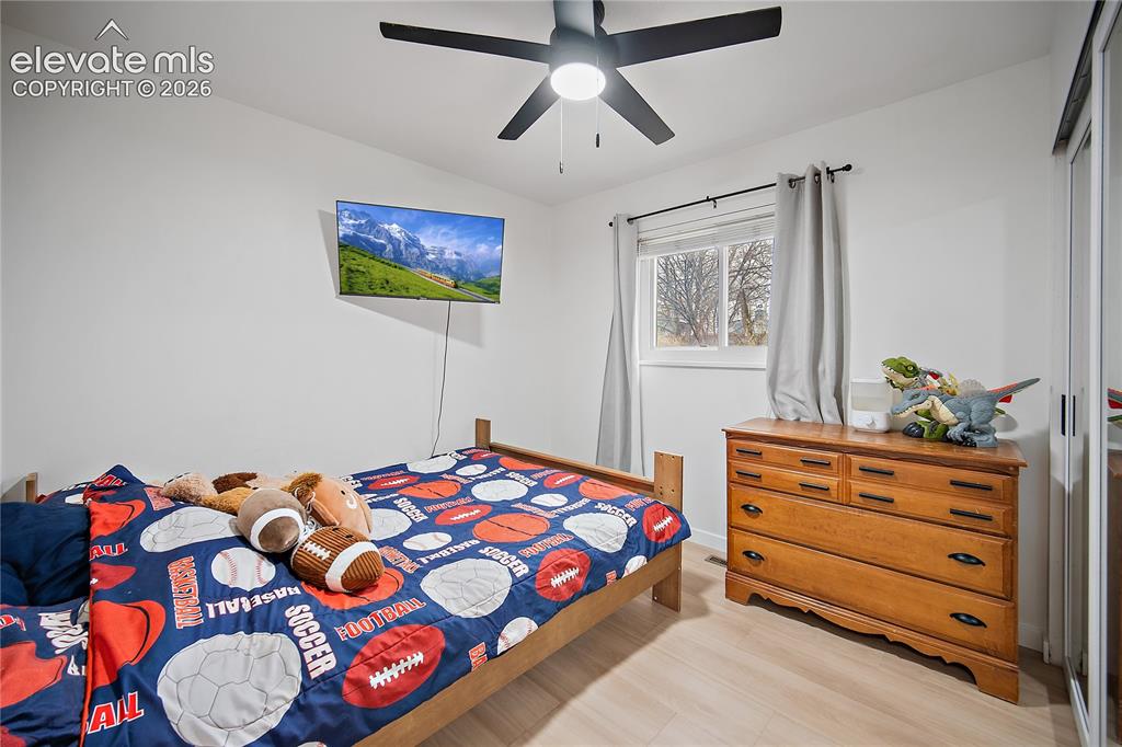 Image 11 of 18: Bright secondary bedroom featuring wood-finish flooring, a ceiling fan with