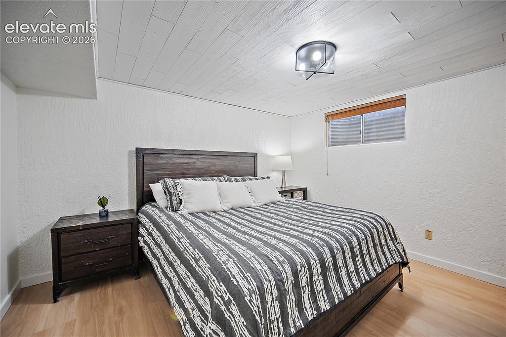 Image 13 of 18: Wood-finish flooring, textured white walls, a wood-paneled ceiling, and a c